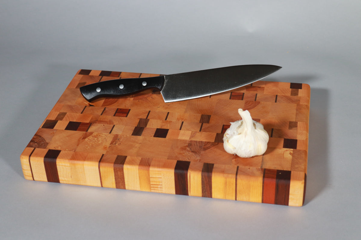 image shows a head of garlic and a chef's knife onan end-grain cutting board to show its scale