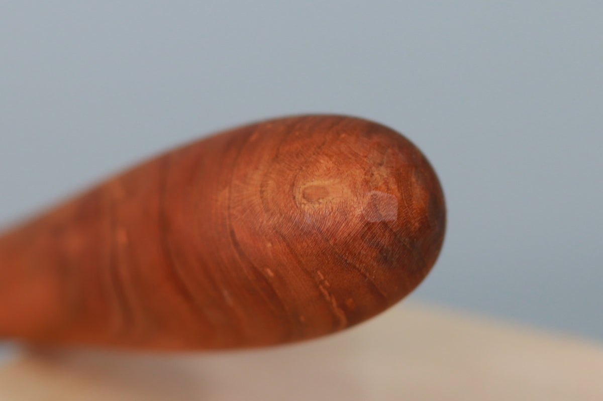 View of pommel end of cherry sauté stirrer showing detail of cherry grain and facets of hand-carved detail.