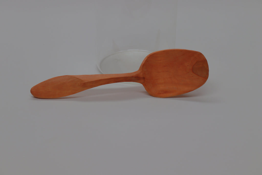 A slightly underexposed view of the whole of the hawthorn serving spoon, lying on its side, fetchingly propped against a nearly invisible glass cylinder. You know you want this spoon. You will give it to your niece as a wedding present, but it's the sort of thing you'll still want a year from now.