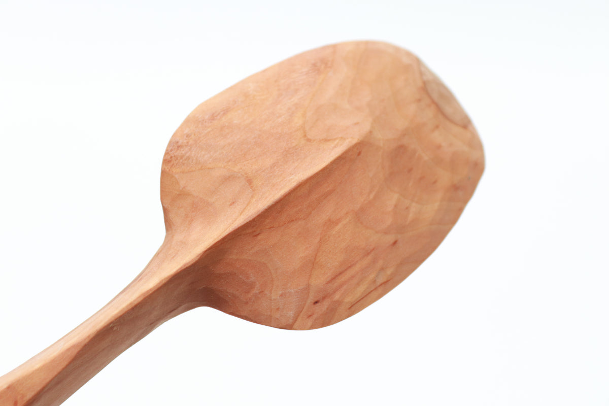 Wooden spoon, seen from the bottom, on a white background. The centerline of the handle is carved to a thin, graceful keel, which extends 2/3 of the way to the front of the spoon's bowl. The hawthorn wood is the color of caramel.