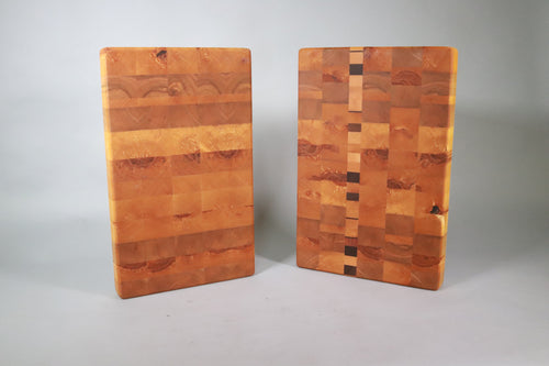 two wooden cutting boards standing upright on a gray background. Vivid patterns in the growth rings add graphic interest.