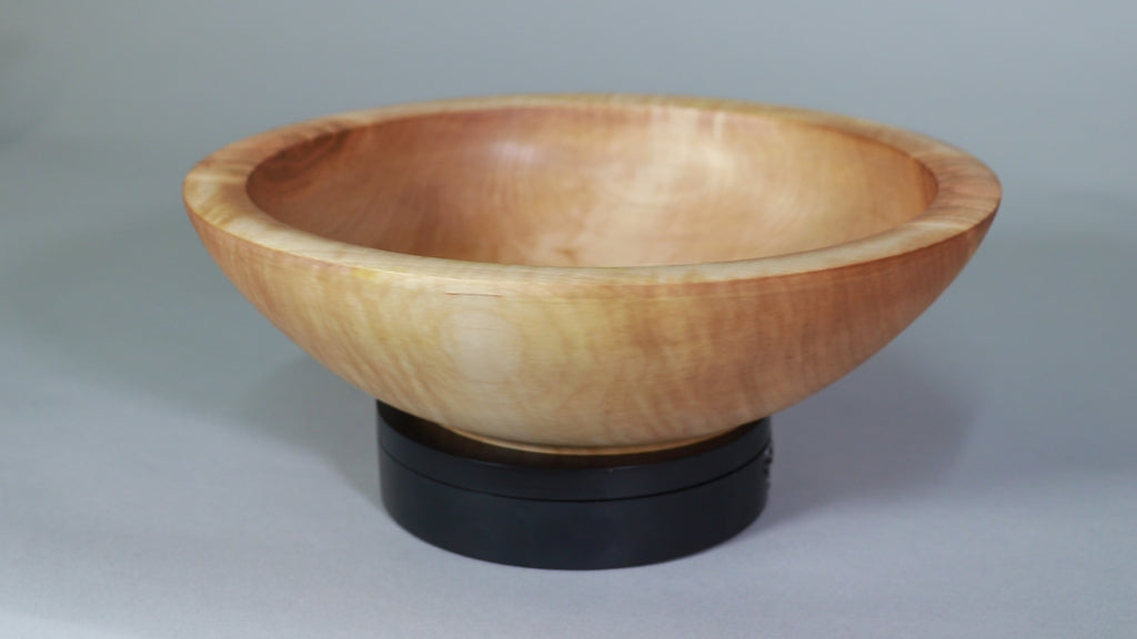 a medium sized maple salad bowl with an ogee shaped base is rotating on a small black turntable