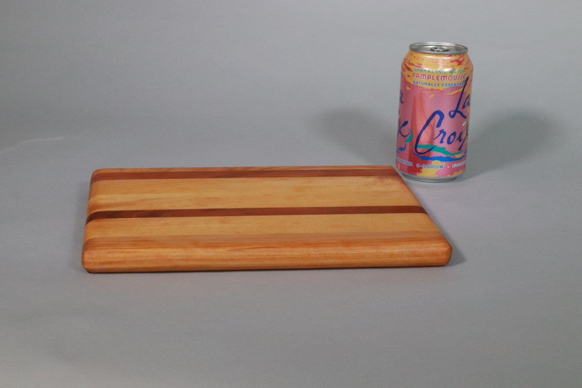 Stripy laminated wooden cutting board next to a can of mineral water against a gray background